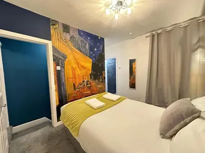 a bedroom with a large bed with a painting on the wall at 5 Mins to Anfield, 2 Bed, Mosaic Art House in Liverpool