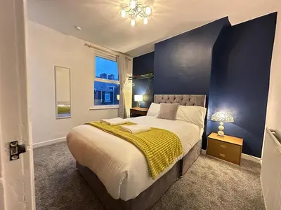 a bedroom with a large bed with a yellow blanket at 5 Mins to Anfield, 2 Bed, Mosaic Art House in Liverpool