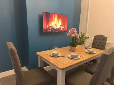 a dining room table with a fireplace on the wall at 5 Mins to Anfield, 2 Bed, Mosaic Art House in Liverpool