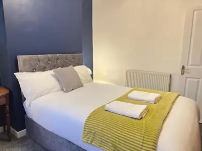 a large bed with two towels on top of it at 5 Mins to Anfield, 2 Bed, Mosaic Art House in Liverpool