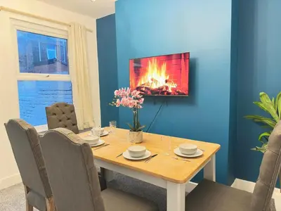 a dining room with a table with a fire on the wall at 5 Mins to Anfield, 2 Bed, Mosaic Art House in Liverpool