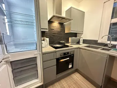 a kitchen with white cabinets and a stove top oven at 5 Mins to Anfield, 2 Bed, Mosaic Art House in Liverpool