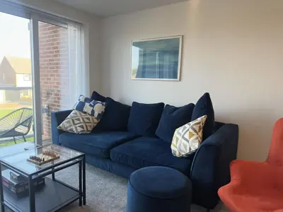 a living room with a blue couch and a table at Coastal 2 Bathroom Apartment, Free Parking in Moreton