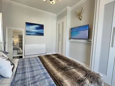 a bedroom with a bed and a tv on the wall at Stylish Highland-Theme 2BR Sefton Park in Liverpool