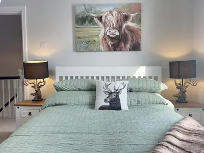 a bedroom with a bed with a painting of a cow at Stylish Highland-Theme 2BR Sefton Park in Liverpool