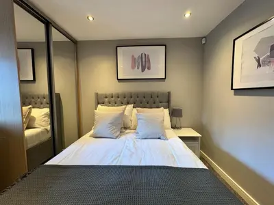 a bedroom with a large white bed with a mirror at Balcony Free Parking Huge TV City Centre Apt in Liverpool