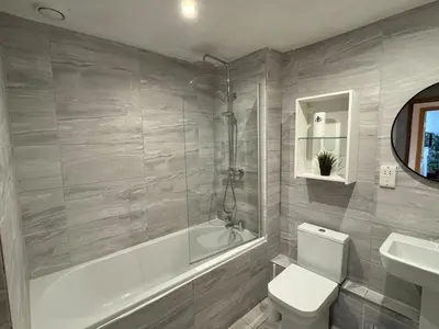 a bathroom with a tub and a toilet and a sink at Balcony Free Parking Huge TV City Centre Apt in Liverpool