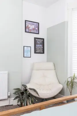 a white chair in a living room with plants at Very Spacious 2 Bath Free Parking in Liverpool