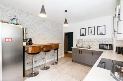 a kitchen with a bar with stools in it at Very Spacious 2 Bath Free Parking in Liverpool