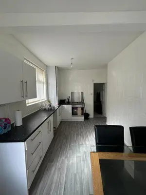 a large kitchen with white cabinets and a wooden floor at Room in Anfield 5 minute walk to stadium in Liverpool