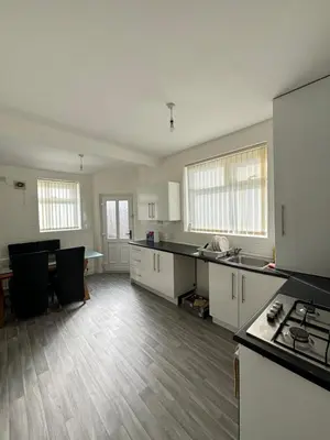 an empty kitchen with white cabinets and a table at Room in Anfield 5 minute walk to stadium in Liverpool