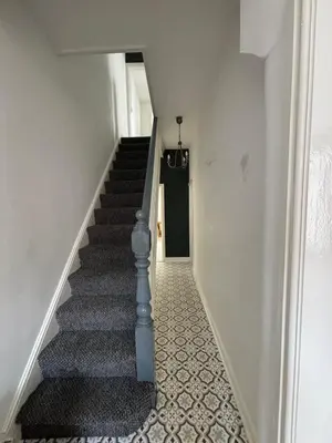a stairway with a blue rail and a black door at Room in Anfield 5 minute walk to stadium in Liverpool