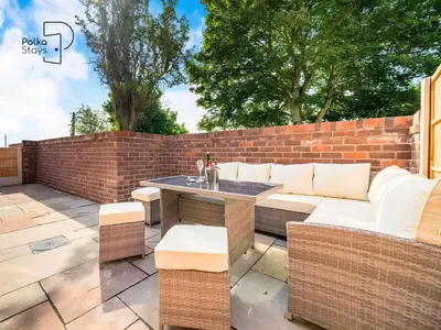 a patio with a couch and a table and a brick wall at No 1 PolkaStays Ivy Farm Willow Cottage in Plumpton