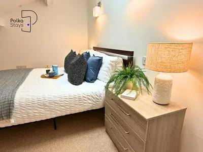 a bedroom with a bed with blue pillows and a lamp at No 1 PolkaStays Ivy Farm Willow Cottage in Plumpton