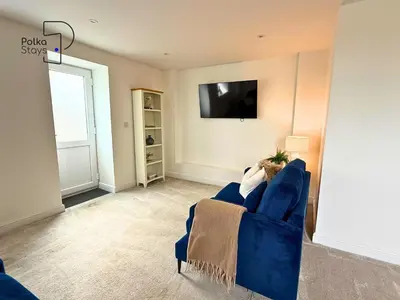 a living room with a blue couch and a tv at No 1 PolkaStays Ivy Farm Willow Cottage in Plumpton
