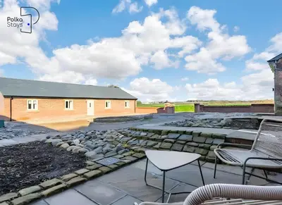 a patio with chairs and rocks and a building at No 5 PolkaStays Ivy Farm Paddock Lodge in Brown Moss Side