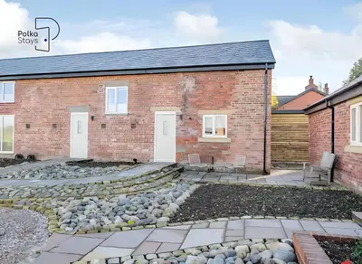 a brick house with a patio and gravel yard at No 5 PolkaStays Ivy Farm Paddock Lodge in Brown Moss Side