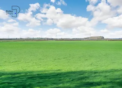 a large green field with a blue sky and clouds at No 5 PolkaStays Ivy Farm Paddock Lodge in Brown Moss Side