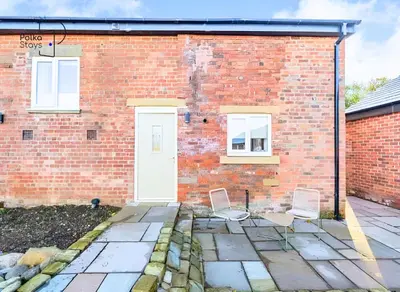 two chairs in front of a brick building at No 5 PolkaStays Ivy Farm Paddock Lodge in Brown Moss Side