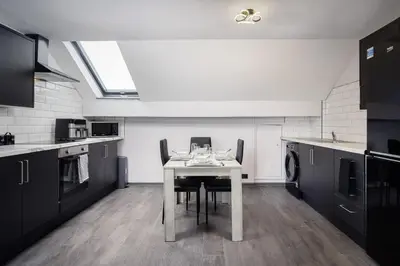 a kitchen with a table and chairs in a room at The Coaster Loft Apartments by STAMP SA in Blackpool