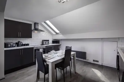 a kitchen with a table and chairs in a room at The Coaster Loft Apartments by STAMP SA in Blackpool
