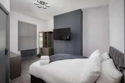 a bedroom with a large white bed and a television at The Coaster Loft Apartments by STAMP SA in Blackpool