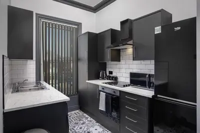 a black and white kitchen with a sink and a microwave at The Coaster Loft Apartments by STAMP SA in Blackpool