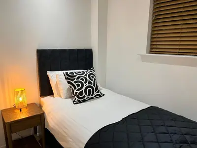 a bed with a black and white pillow and a lamp at Oceans 45 in Blackpool