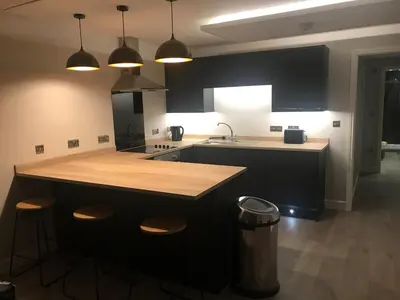 a kitchen with a counter and a island with stools at Barrow Centre Stylish 1 Bed flat in Barrow in Furness