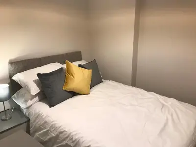a white bed with three pillows on top of it at Barrow Centre Stylish 1 Bed flat in Barrow in Furness