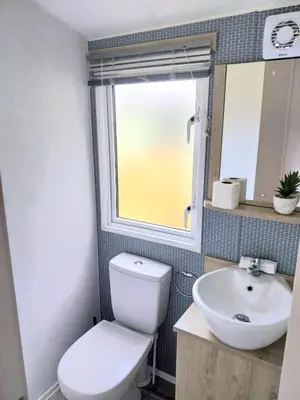 a bathroom with a toilet and a sink and a window at Luxury 6 berth Caravan Lytham in Preston