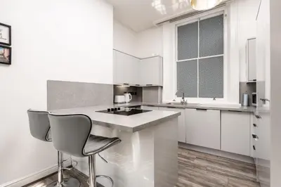 a white kitchen with a sink and two chairs at Castle St Steps to Ivy Washer Pet-Friendly in Liverpool