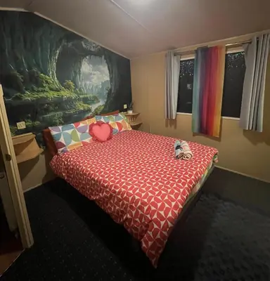 a bedroom with a bed with a red comforter at The Rainbow's nest in Morecambe