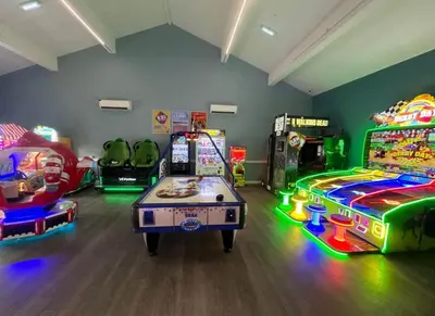 a room with several arcade games and a game table at The Rainbow's nest in Morecambe