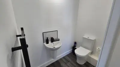a white bathroom with a toilet and a sink at Spacious & Modern house in St Helens in Saint Helens