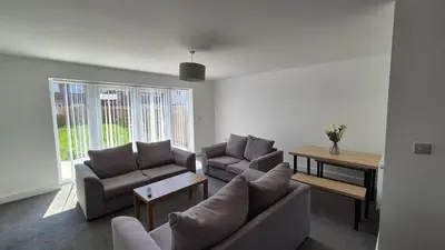 a living room with two couches and a table at Spacious & Modern house in St Helens in Saint Helens