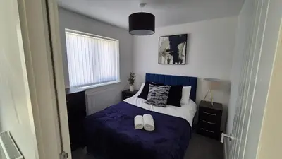 a bedroom with a bed with a purple comforter and two shoes at Spacious & Modern house in St Helens in Saint Helens