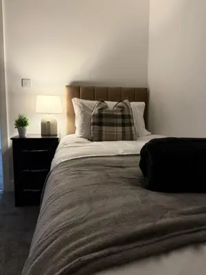 a bedroom with a bed with a pillow and a lamp at Spacious & Modern house in St Helens in Saint Helens