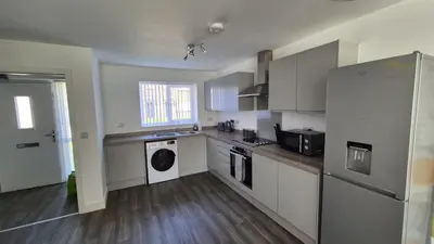 a kitchen with white cabinets and a washer at Spacious & Modern house in St Helens in Saint Helens