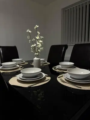 a black table with chairs and plates and a vase with flowers at Comfortable and Modern Living house in St Helens in Saint Helens