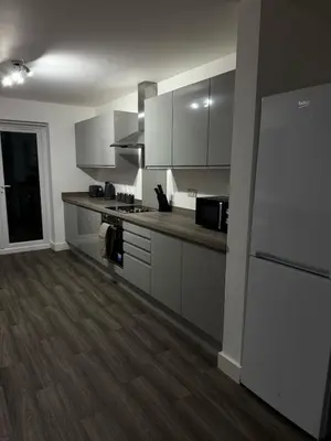a kitchen with white cabinets and a refrigerator at Comfortable and Modern Living house in St Helens in Saint Helens