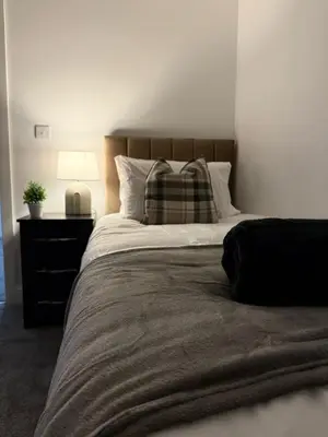 a bedroom with a bed with a pillow and a lamp at Comfortable and Modern Living house in St Helens in Saint Helens