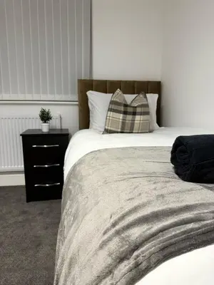 a bedroom with a bed with a pillow and a nightstand at Comfortable and Modern Living house in St Helens in Saint Helens