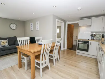 a kitchen and living room with a wooden table and chairs at Threagill in Carnforth