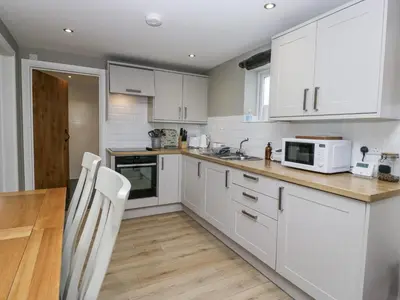 a kitchen with white cabinets and a table and chairs at Threagill in Carnforth