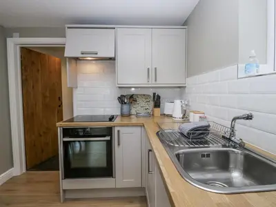 a kitchen with white cabinets and a sink at Threagill in Carnforth