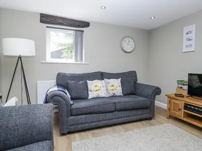 a living room with a couch and a clock on the wall at Threagill in Carnforth