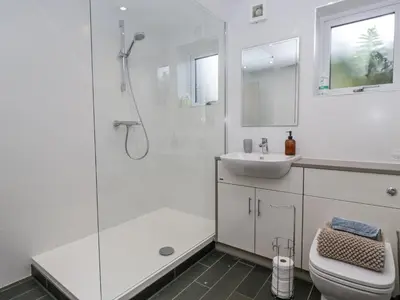 a white bathroom with a shower and a sink at Threagill in Carnforth
