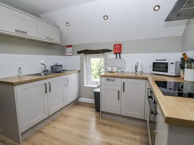 a kitchen with white cabinets and a sink and a window at Treacle in Carnforth