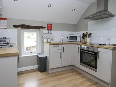 a kitchen with white cabinets and a sink and a microwave at Treacle in Carnforth